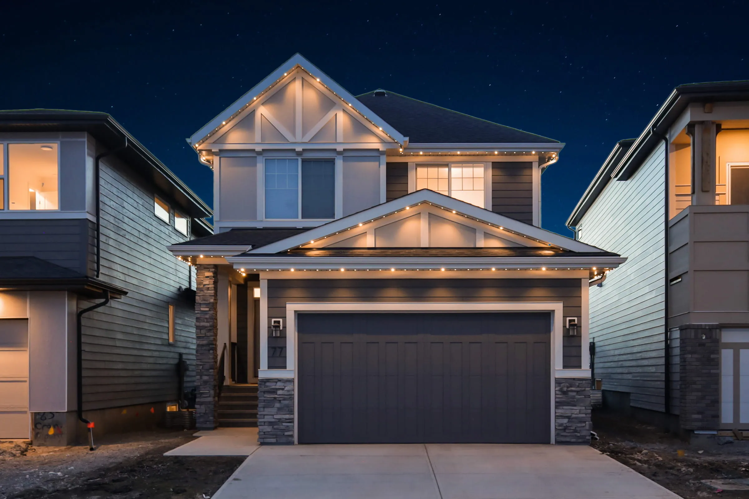 The same home with warm white permanent lights along every roofline