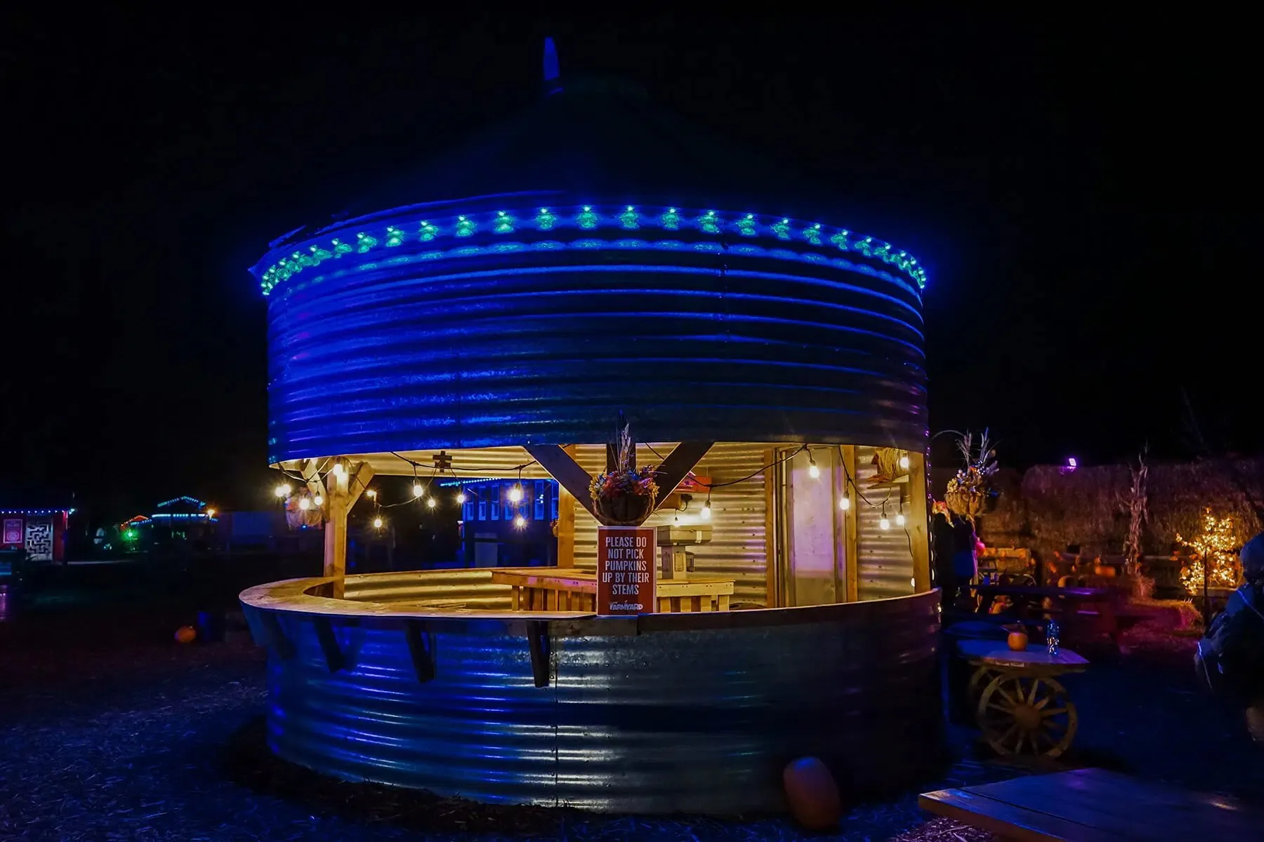 Grain-bin event venue outlined in blue permanent lights at night