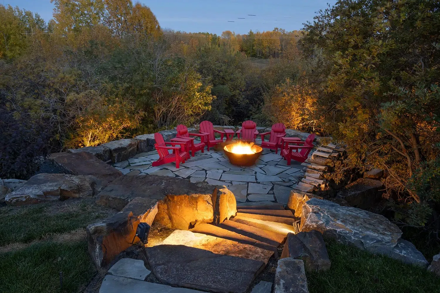 Stone fire pit patio lit warmly at dusk