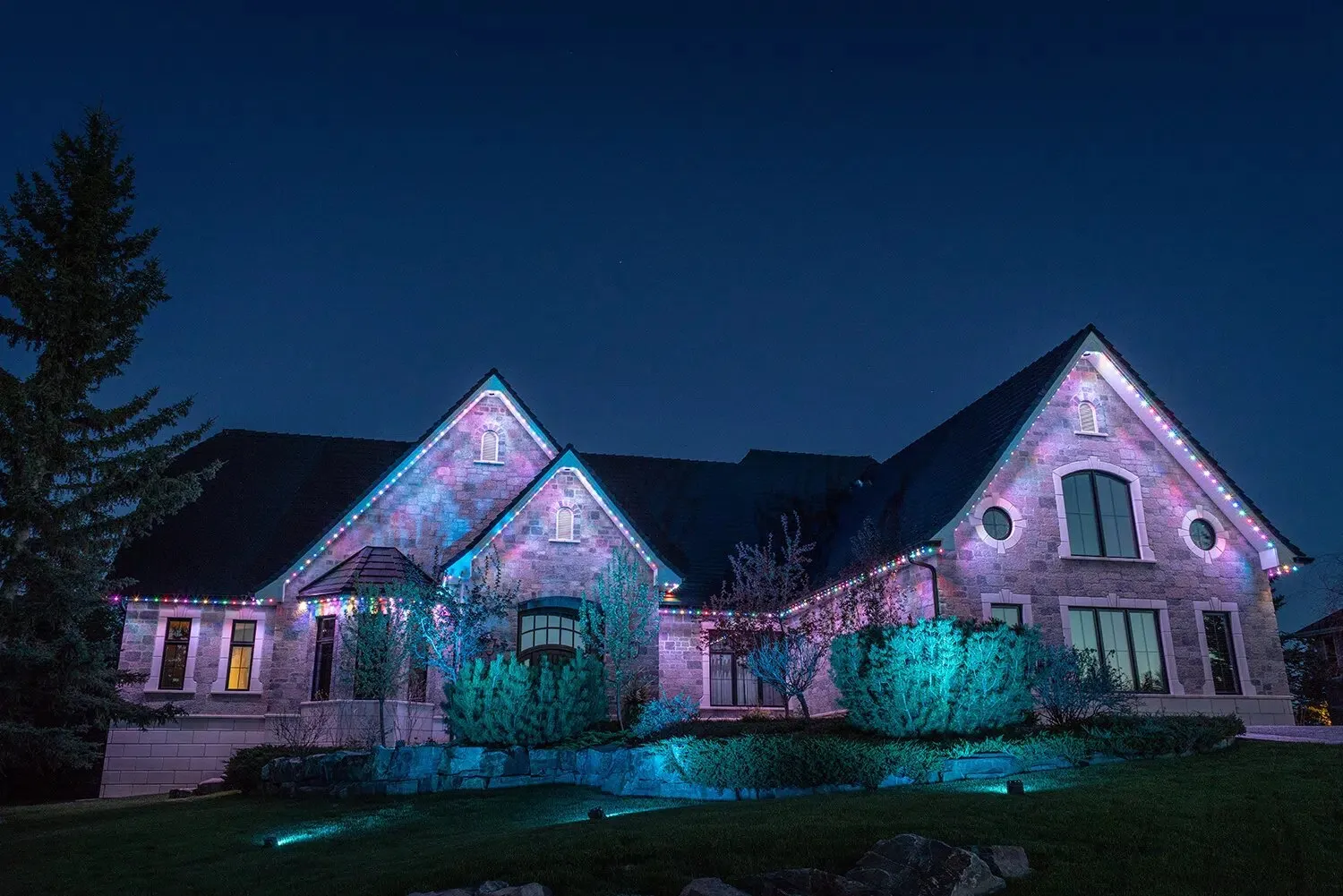 House facade washed with pink and teal flood lighting