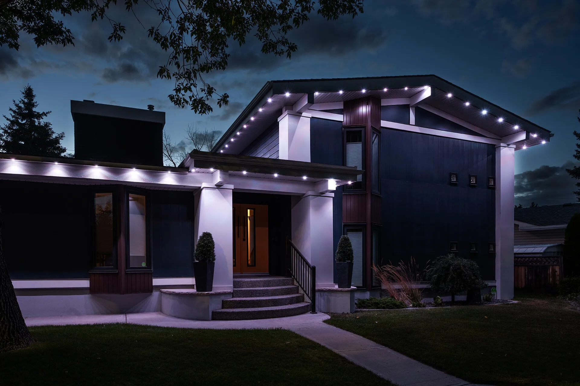 Contemporary home with bright white roofline lighting at night