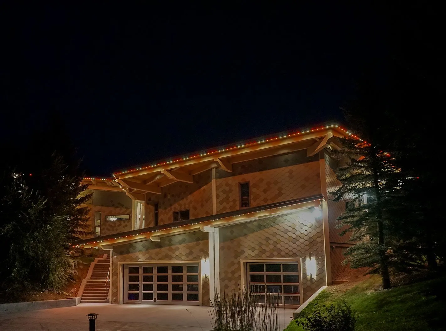 Two-storey home with multicolour permanent roofline lights at night
